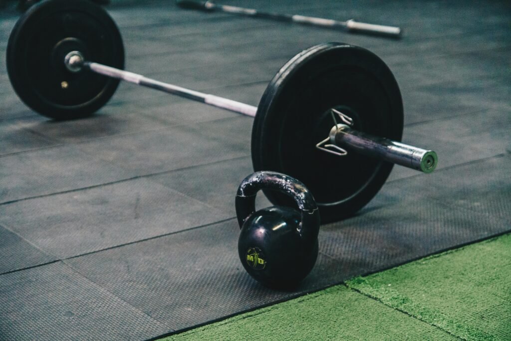 pexels-photo-6628962-6628962 Barbell and kettlebell on gym floor, ideal for fitness and strength training themes.